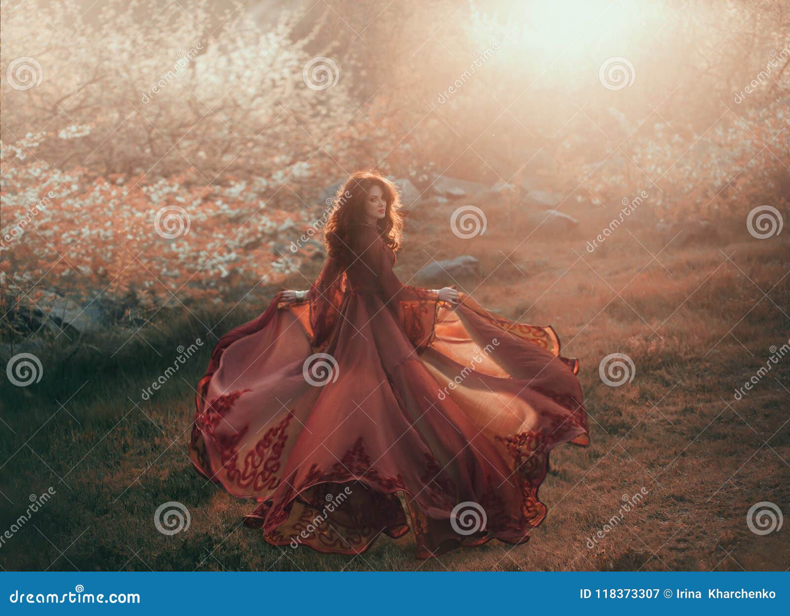 a brunette girl with wavy, thick hair runs to the sun and looks back. the princess has a luxurious, chiffon, red dress