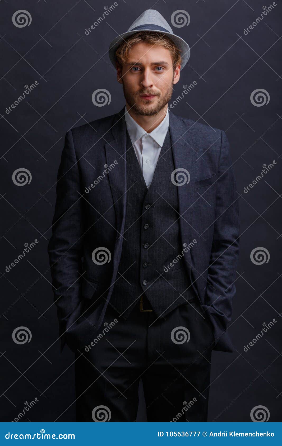 A Brunette Man in a Suit and Hat, Stands with a Serious Look and Grits ...