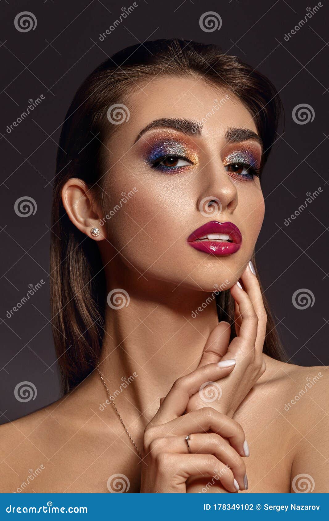 Naked Lady In Jewelry Is Touching Her Face Posing On Gray Background