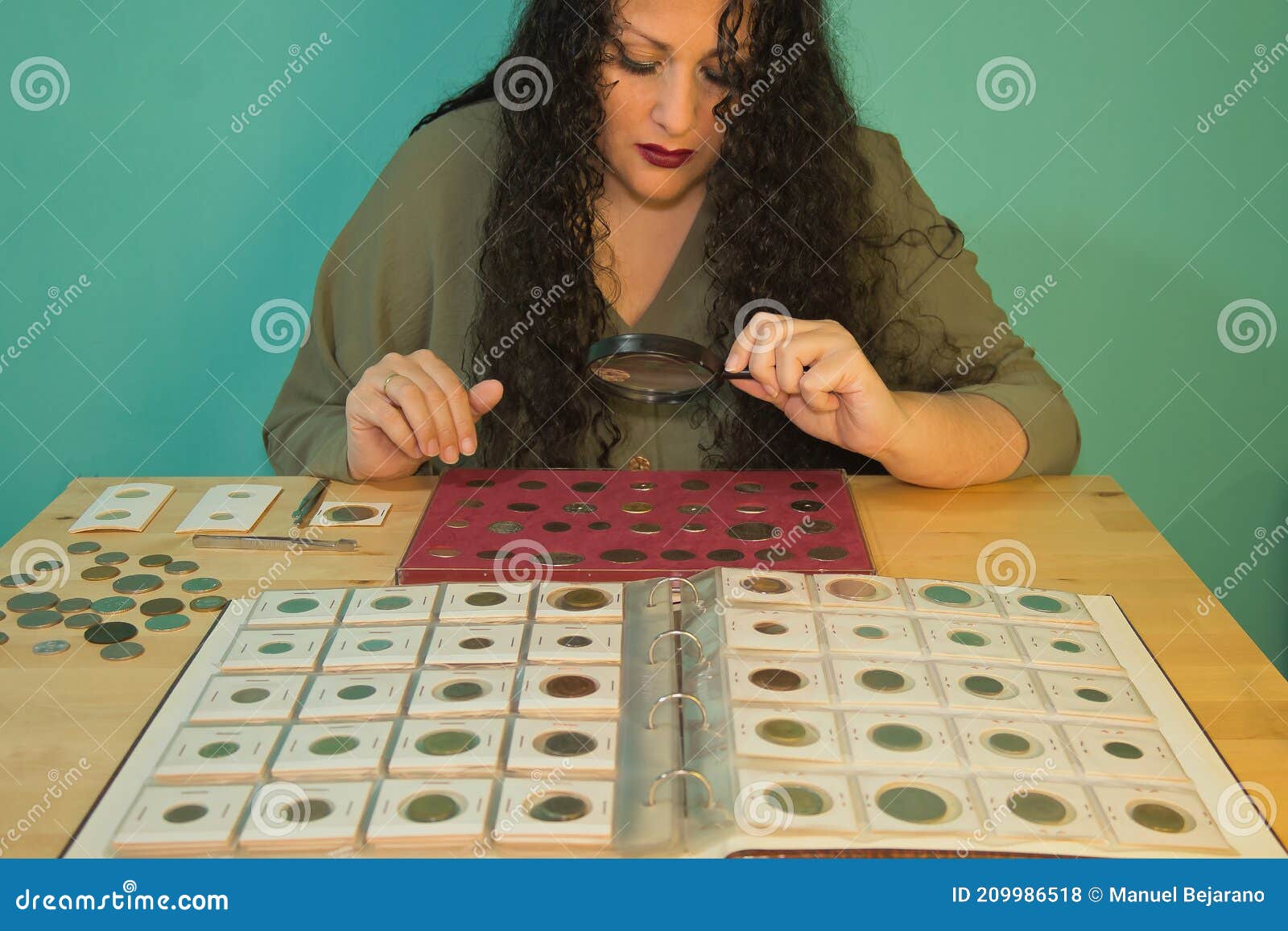 brunette woman with a magnifying glass looking through her numismatic collection