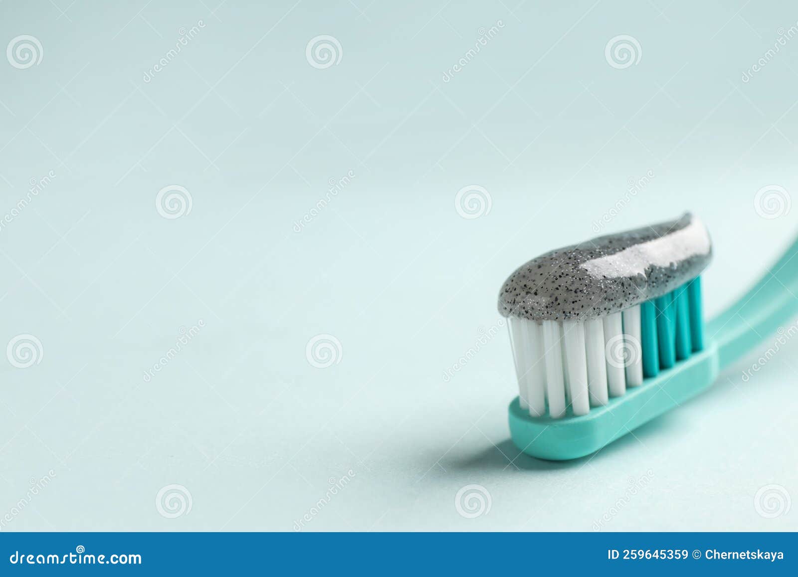 Brush with Charcoal Toothpaste on Light Background, Closeup. Space for