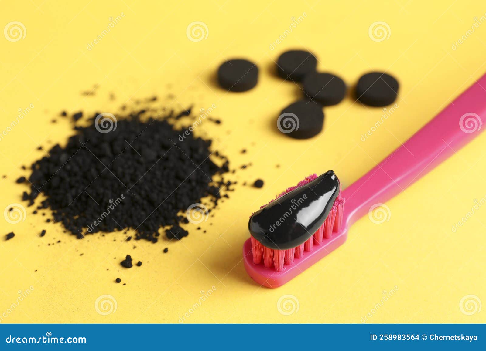 Brush with Charcoal Toothpaste, Powder and Tablets on Yellow Background
