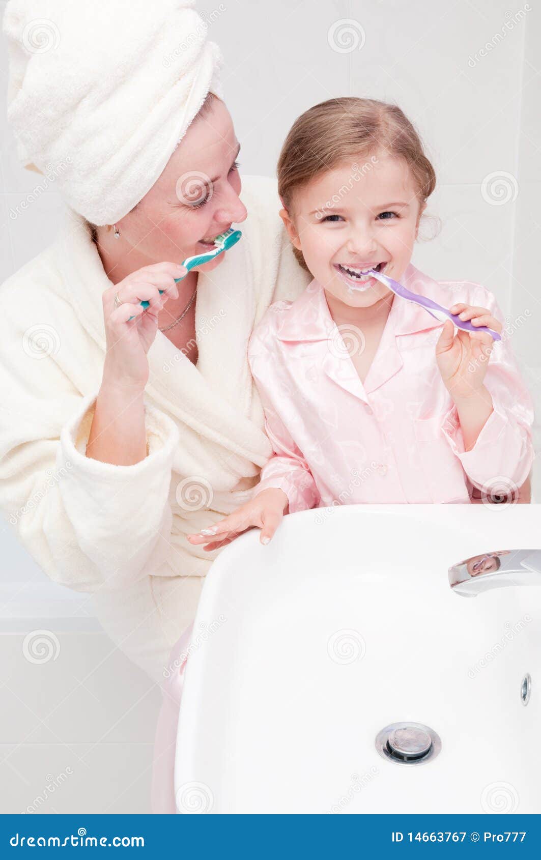 Brushing teeth together. Little girl with mother brushing teeth in bathroom