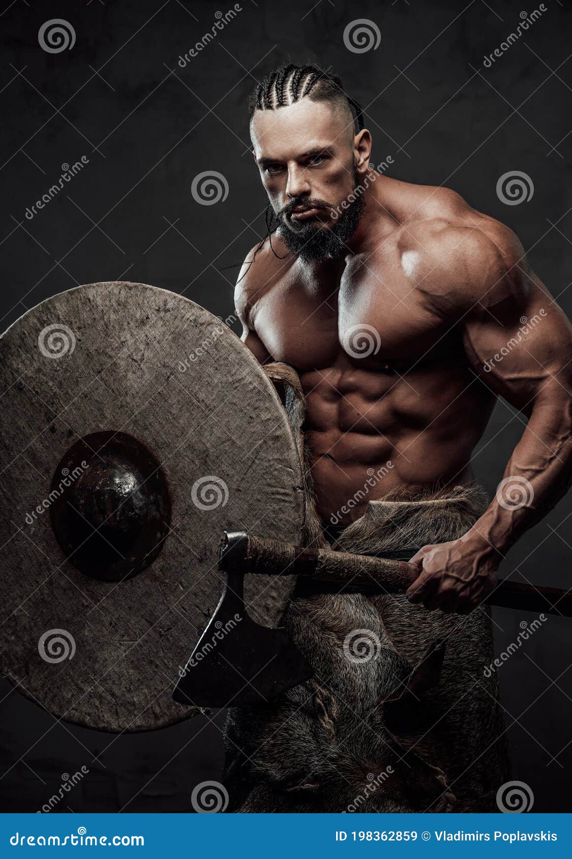 Muscular guy dressed like ancient viking posing in studio with dark backgro...