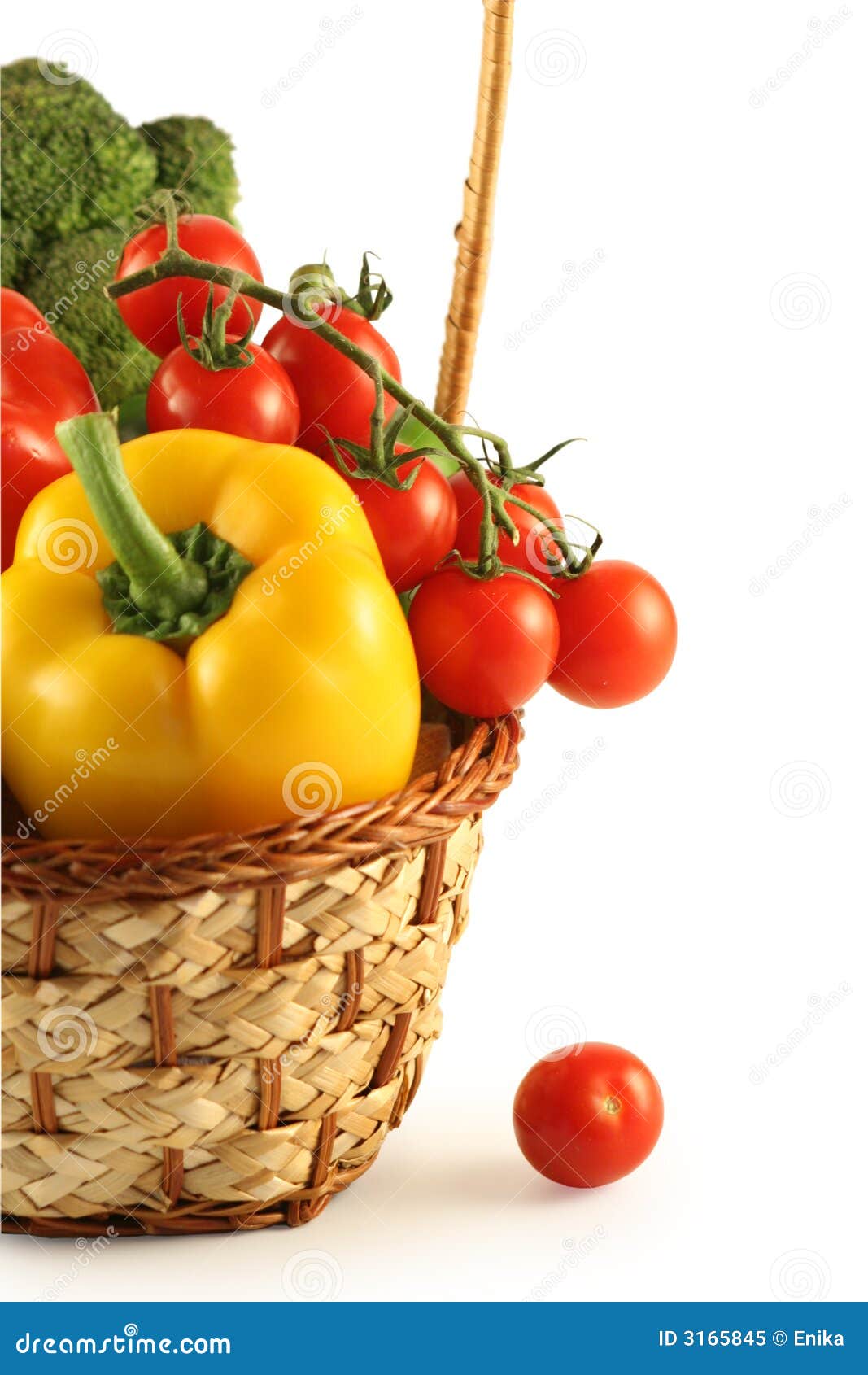 Bróculos, pimenta, e tomates em uma cesta em um fundo branco.