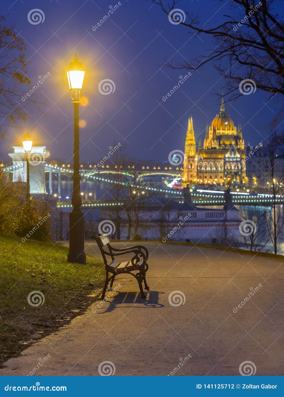 budapest, hungary - bench and lamp post in a park at buda district with parliament of hungary adn szechenyi chain bridge