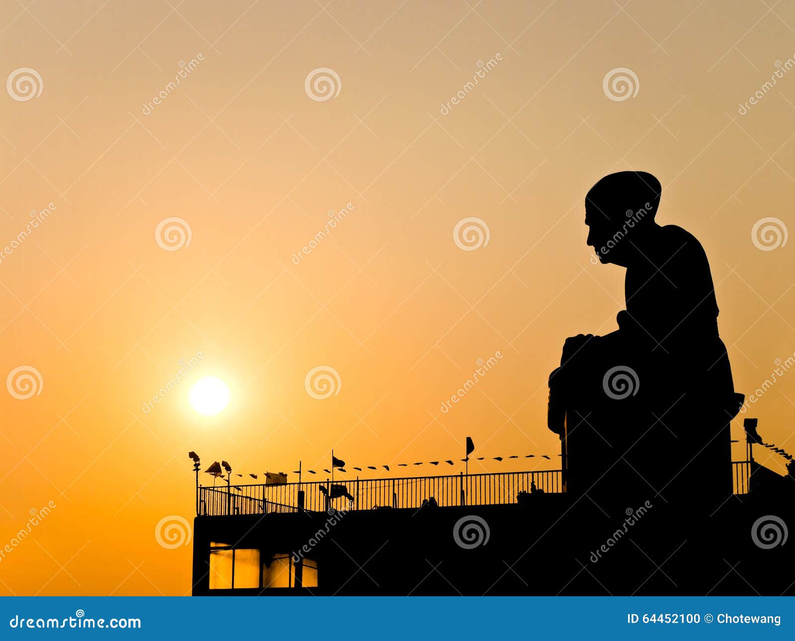 Buddhist monk statue silhouetted. Silhouette view of Buddhist monk statue with twilight sun