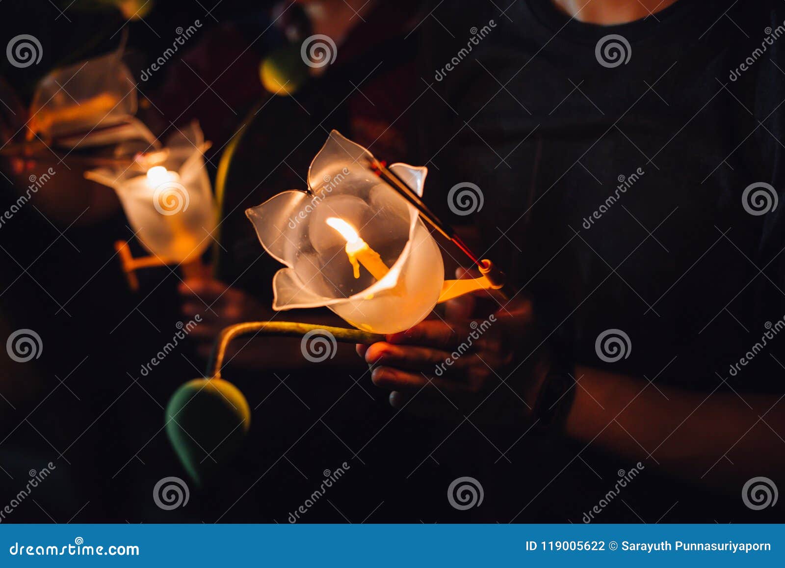 buddhist praying with incense sticks, lotus flower and candles on holy religion day of vesak at night.