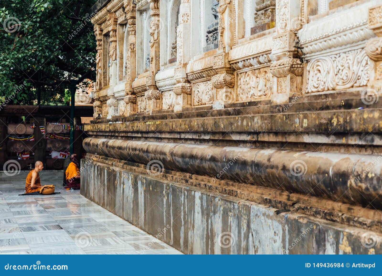 Buddhist monk in meditation under Bodhi Tree in the area of Mahabodhi Temple while raining at Bodh Gaya, Bihar, India.