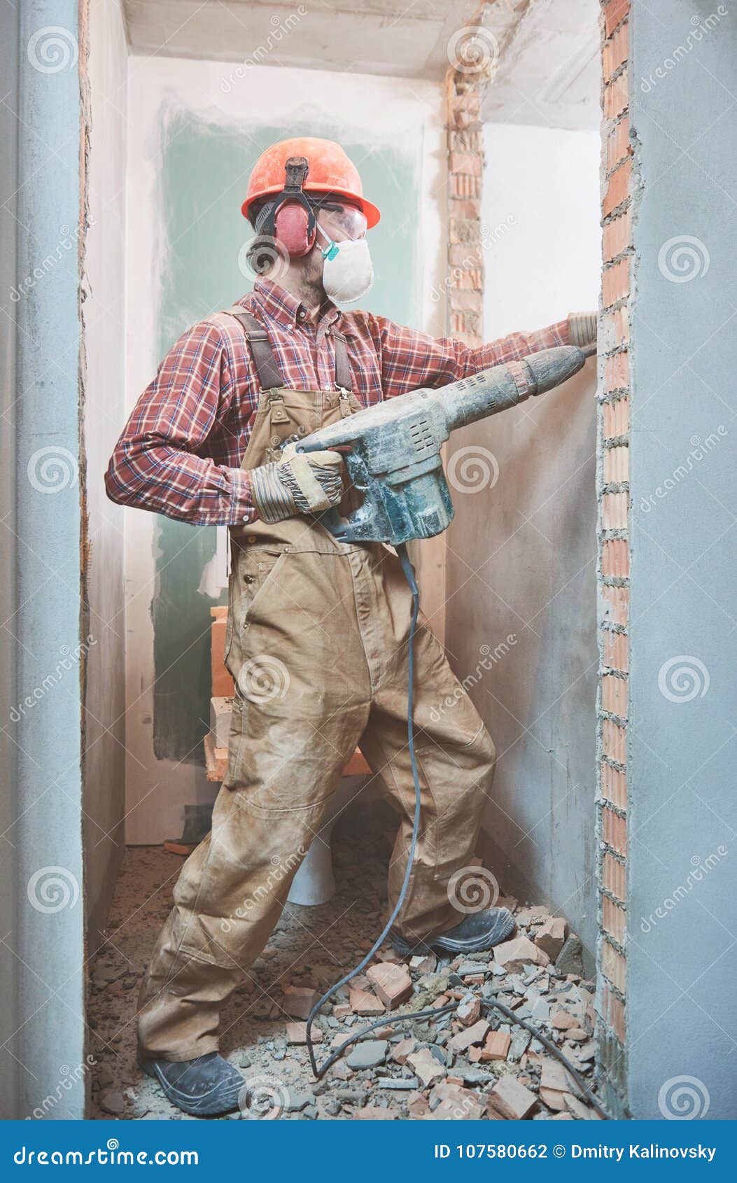 Builder with Demolition Hammer Breaking Interior Wall Stock Photo