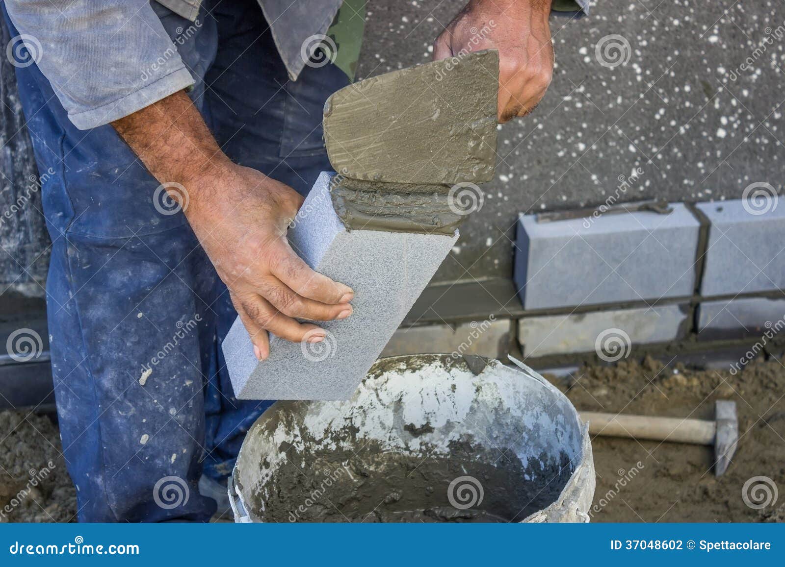 Builder Holding a Brick and with Masonry Trowel Spreading and Sh Stock
