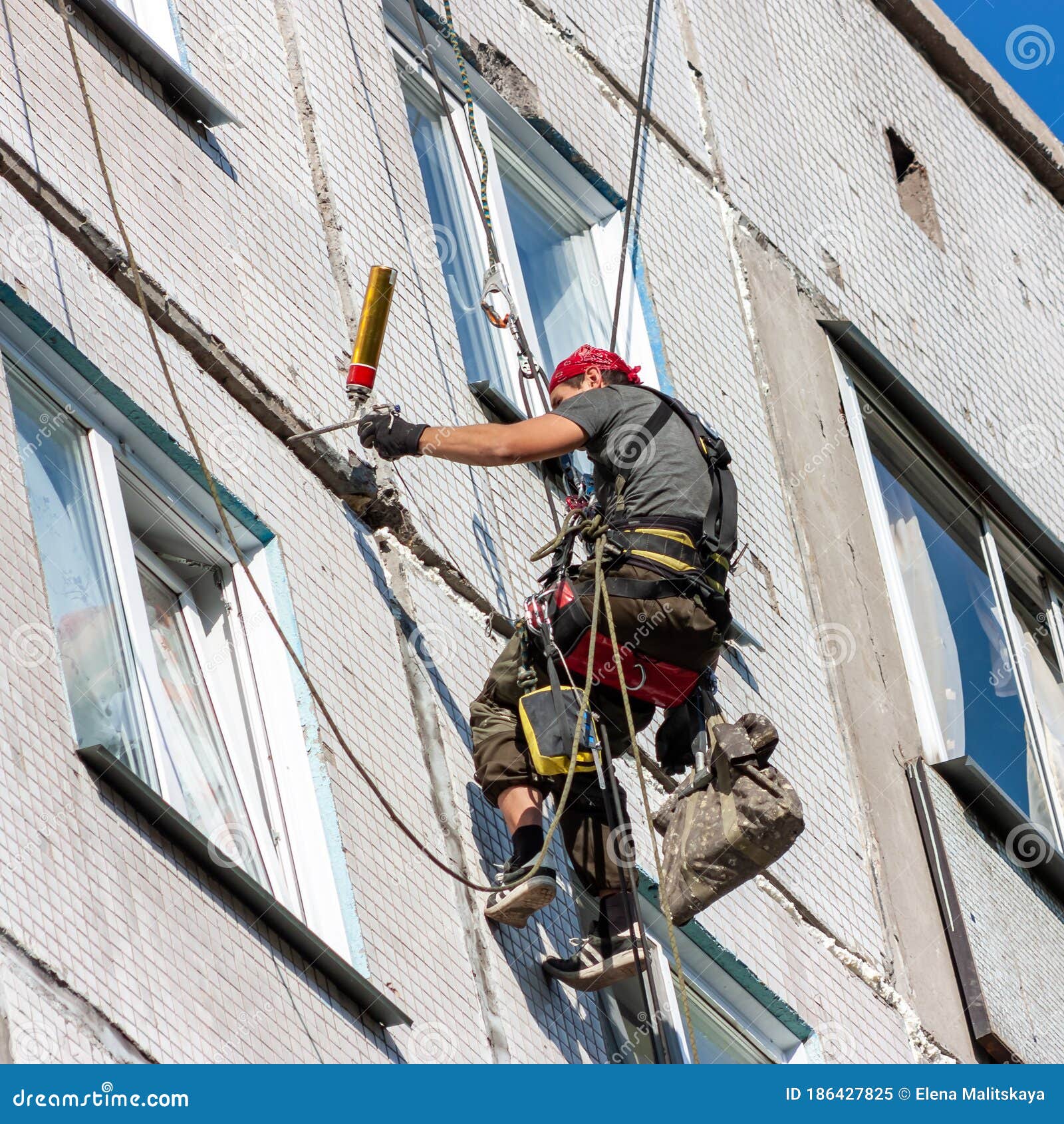 The Builder of an Industrial Climber Hangs on Safety Ropes on the Brick