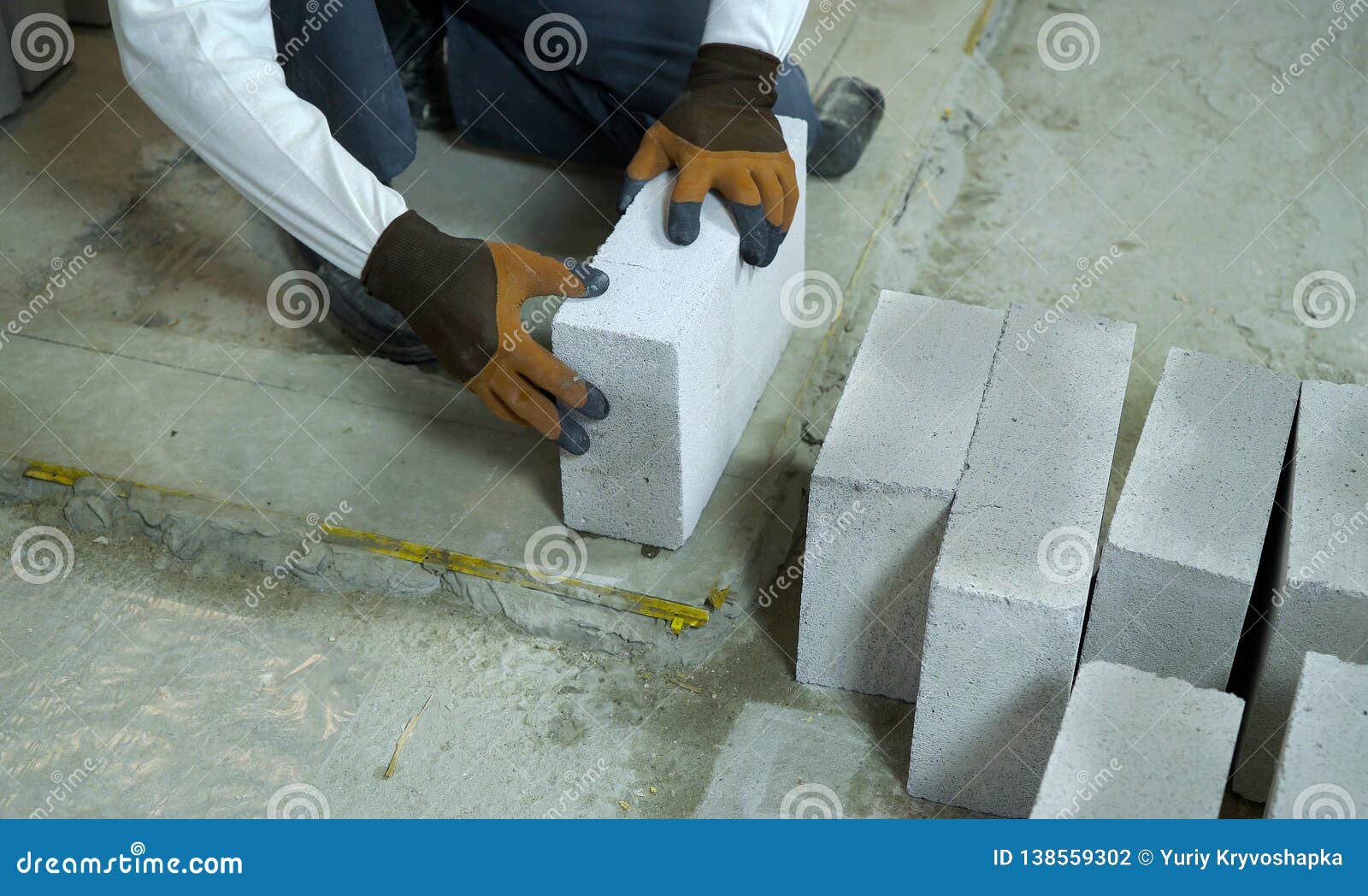 Builder Laying Aerated Concrete Block on Cement Foundation Stock Photo