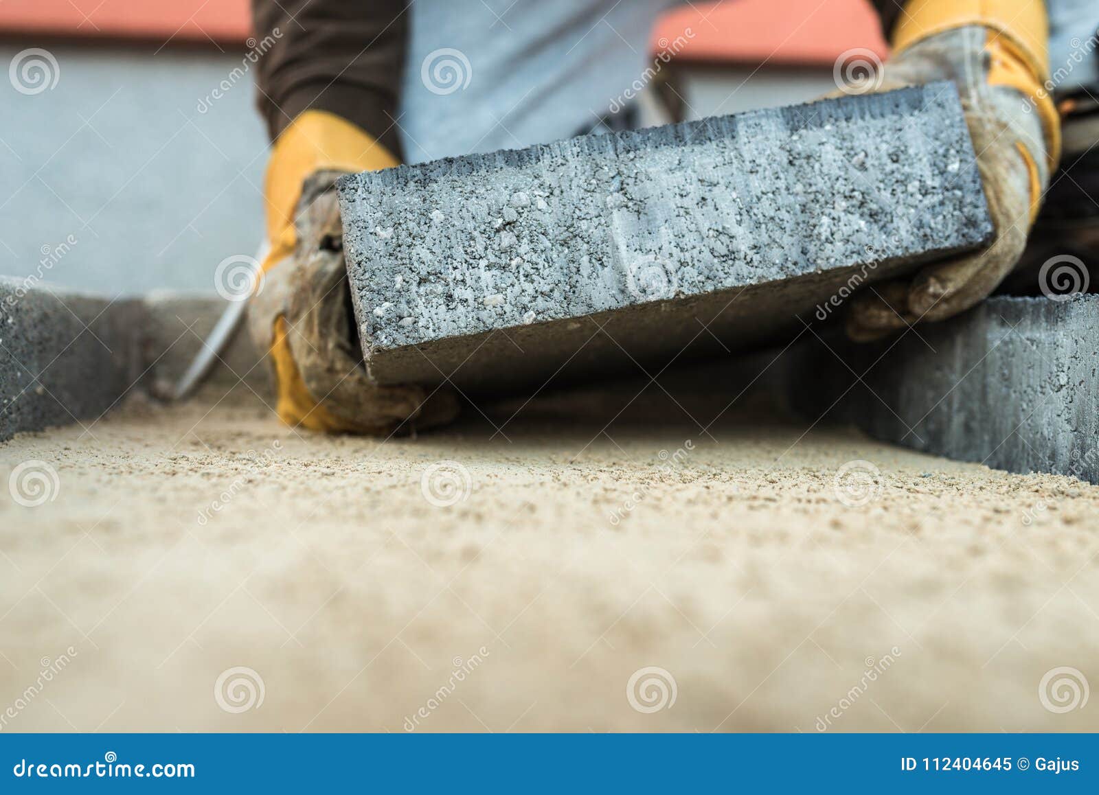 builder laying a paving brick placing it on the sand foundation