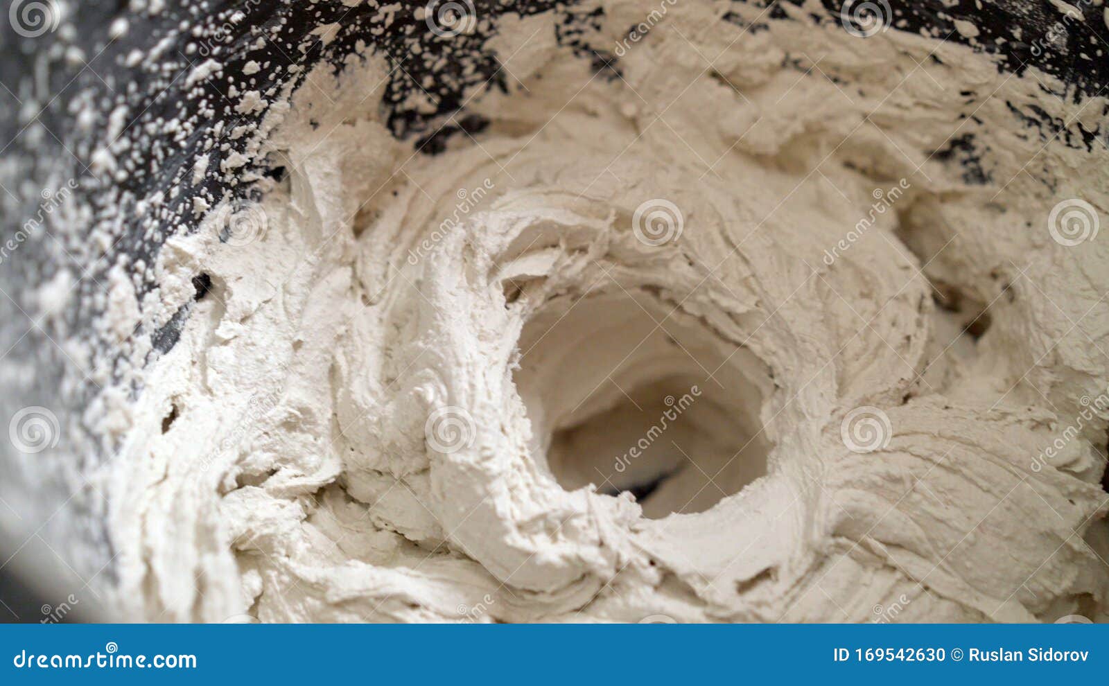 Builder Mixing Tile Glue in a Bucket Using an Electric Mixer. Mixing