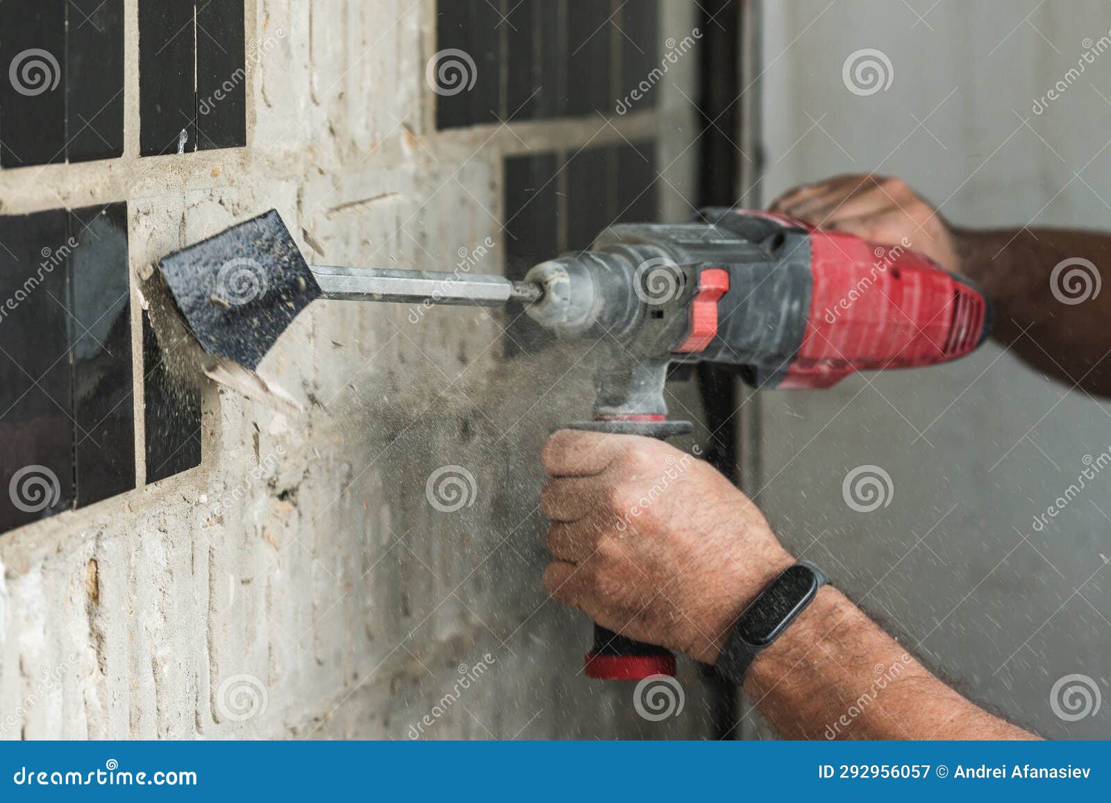 Builder with a Puncher Dismantles Old Tiles from a Concrete Wall Stock