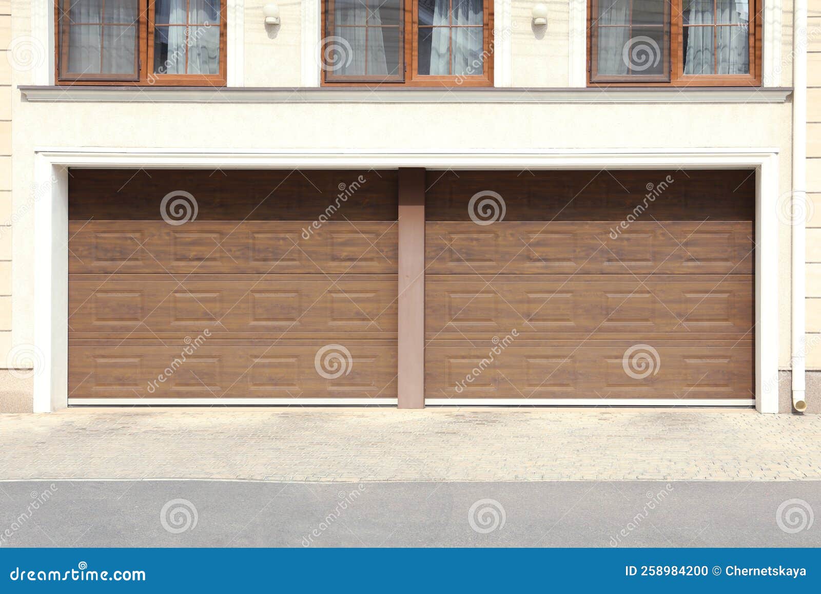 Building with Double Brown Sectional Garage Door on Sunny Day Stock