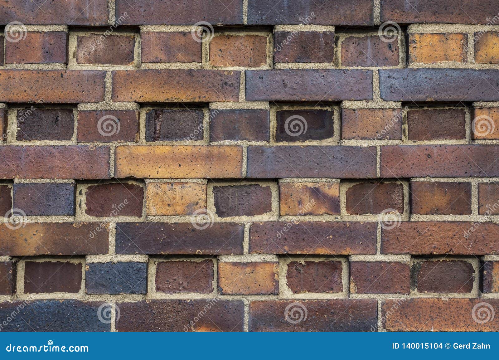 building wall made of dark, yellow to brownish clinker bricks with various alternating patterns. the stones are offset in rows,