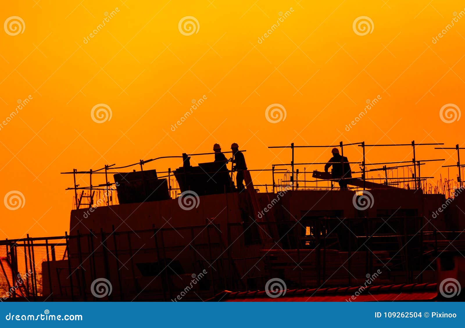 building workers working on a building under a sunset