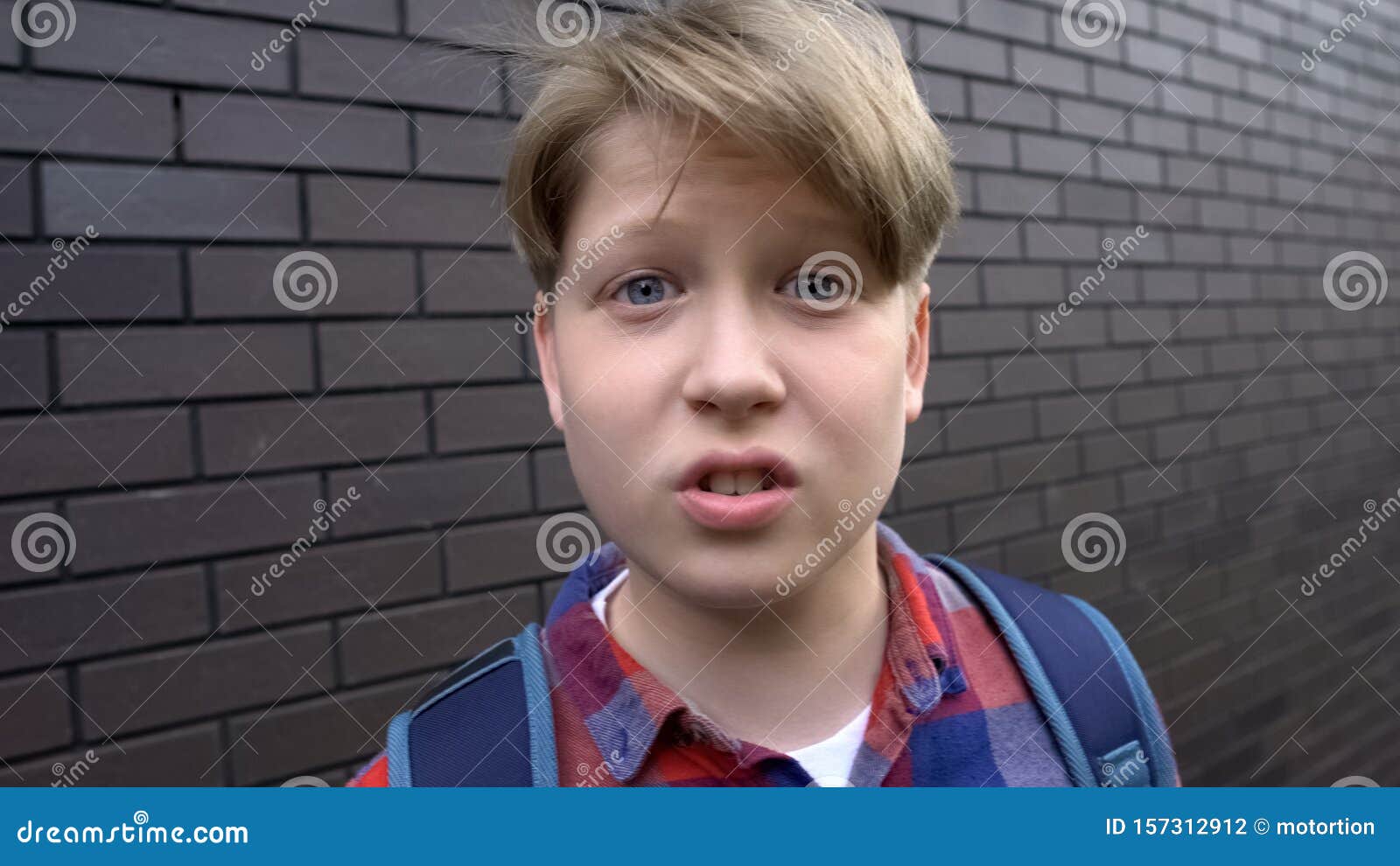 Bully boy teasing into camera, expressing aggression, POV victim of bullying