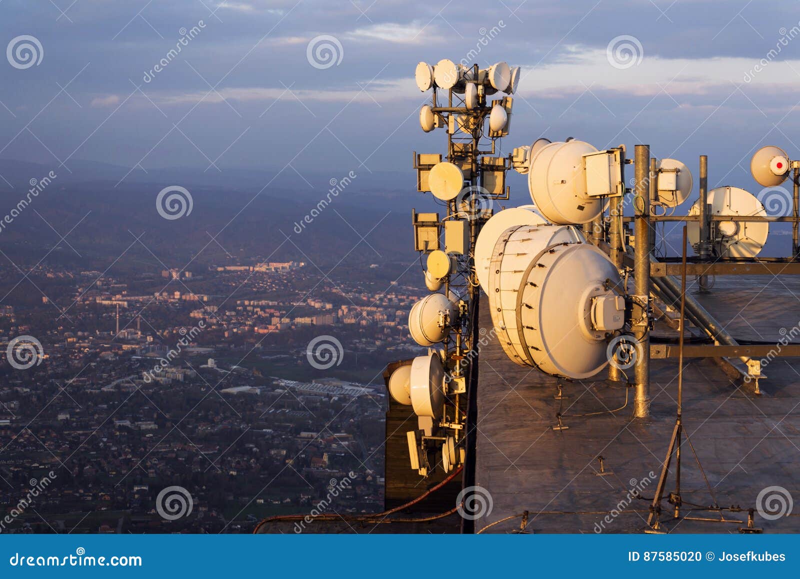 bunch of transmitters and aerials on the telecommunication tower during sunset