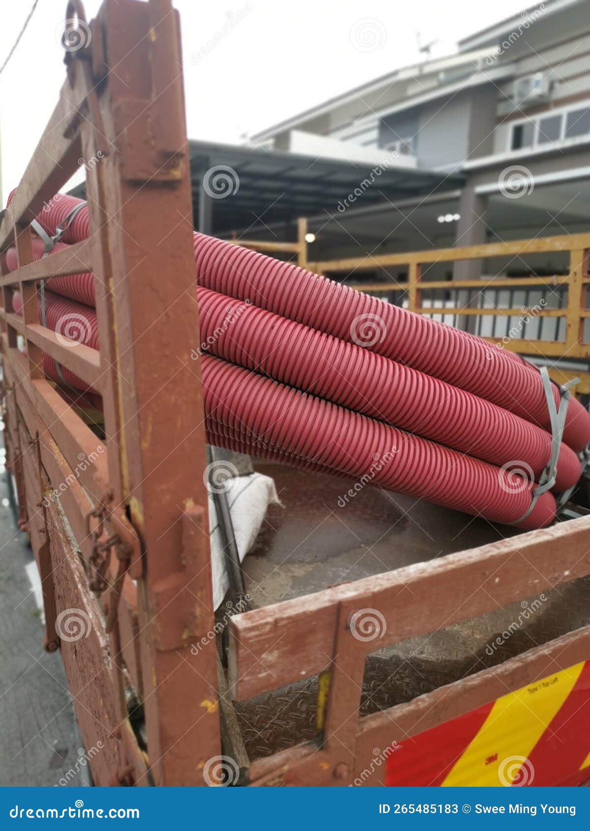 bundle of vermilion red pvc plastic industrial pipe hose at the back of the trunk.