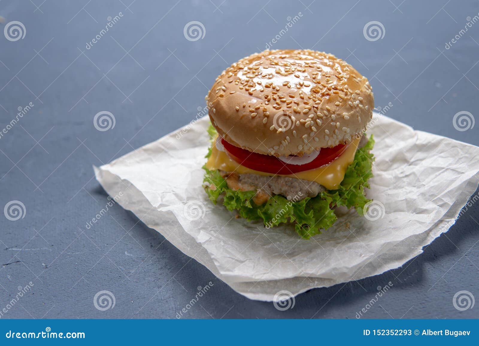 Burger mit Rindfleischpastetchen, Salat, einer Scheibe der Tomate und des Käses, Zwiebeln und Soße mit Paprika in einem gegrillten Brötchen mit indischem Sesam, Amerikaner, Hintergrund, bbq, Brett, Brot, Gelenk, Burger, Cheeseburger, Klassiker, Nahaufnahme, köstlich, Abendessen, schnell, Nahrung, frisch, grün, Hamburger, gesund, lokalisiert, saftig, Kram, Blatt, Kopfsalat, Mittagessen, Mahlzeit, Fleisch, geschmolzen, organisch, Pastetchen, Rot, Restaurant, rustikal, Sandwich, Imbiss, Tabelle, geschmackvoll, ungesund, Gemüse, hölzern