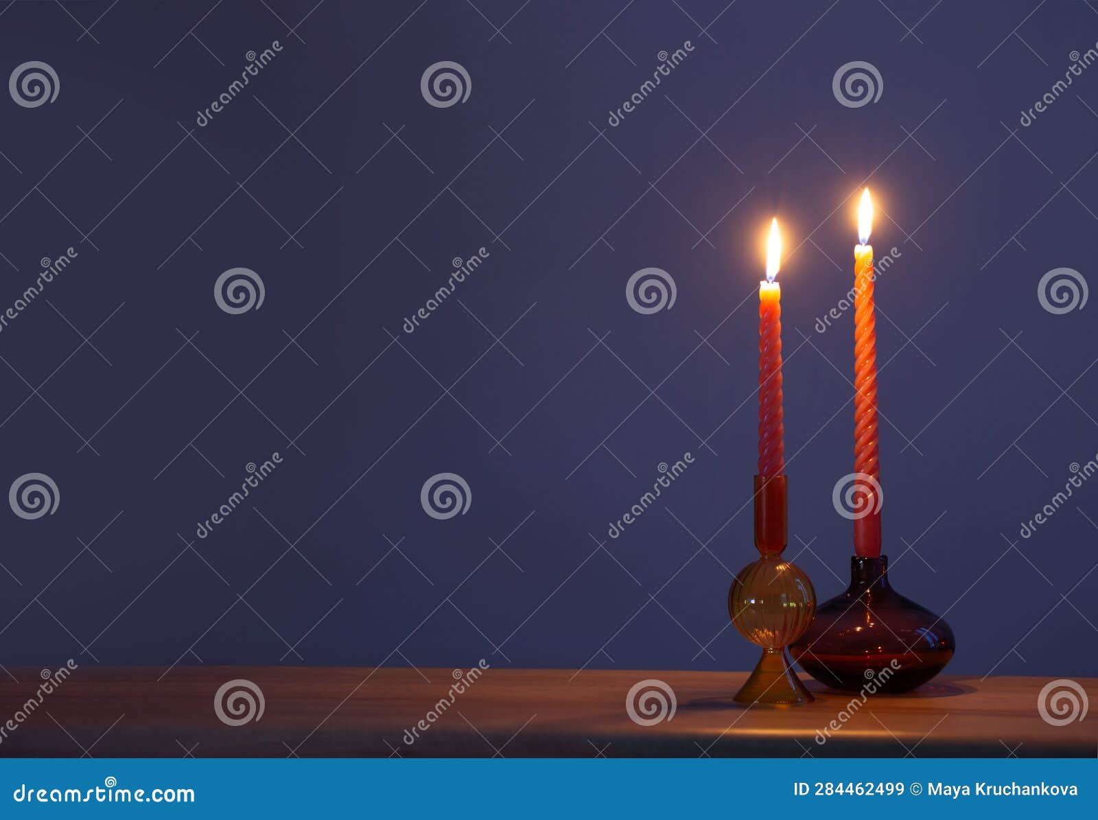 Burning Candles in Glass Candlesticks on Dark Blue Background Stock