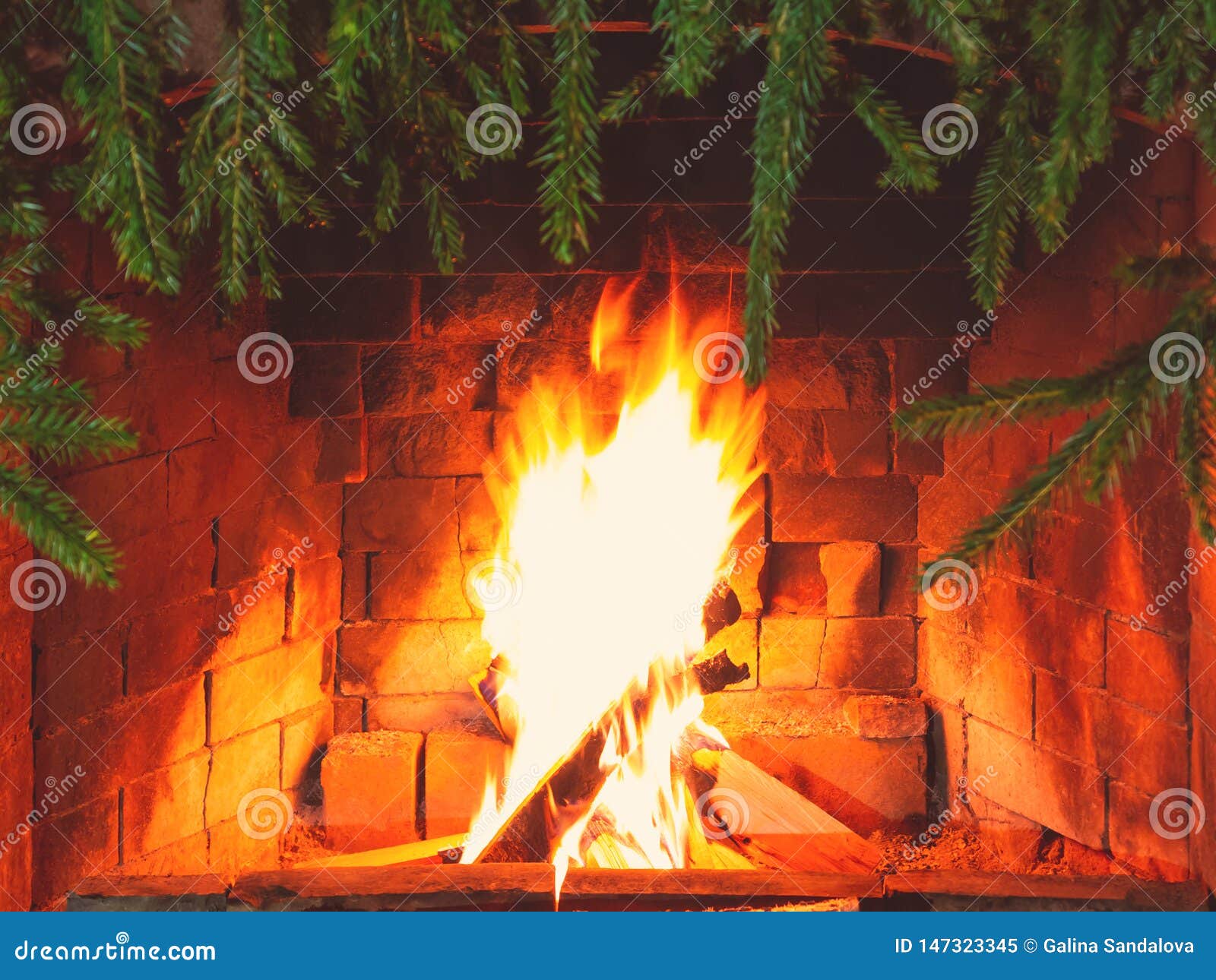 Burning Firewood in a Fireplace Decorated for Christmas with Branches