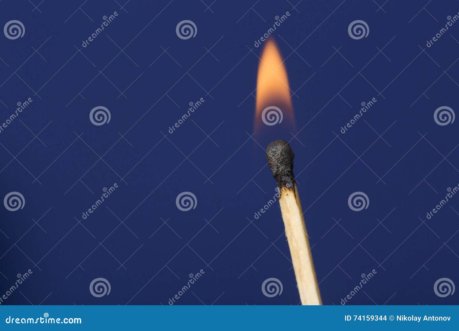 Burning match stick against dark blue background