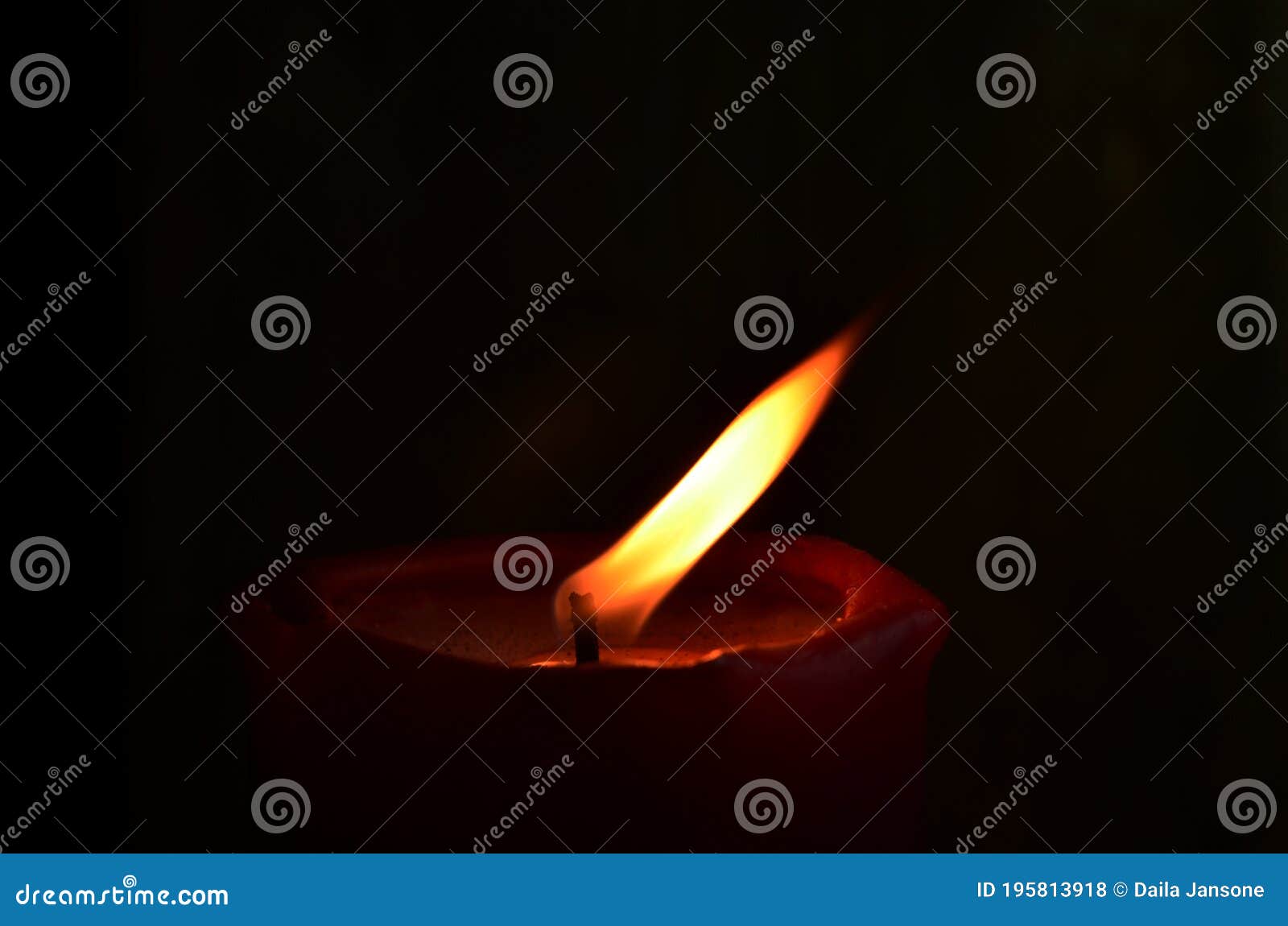 Burning Single Red Candle with Dancing Flame on the Dark Background