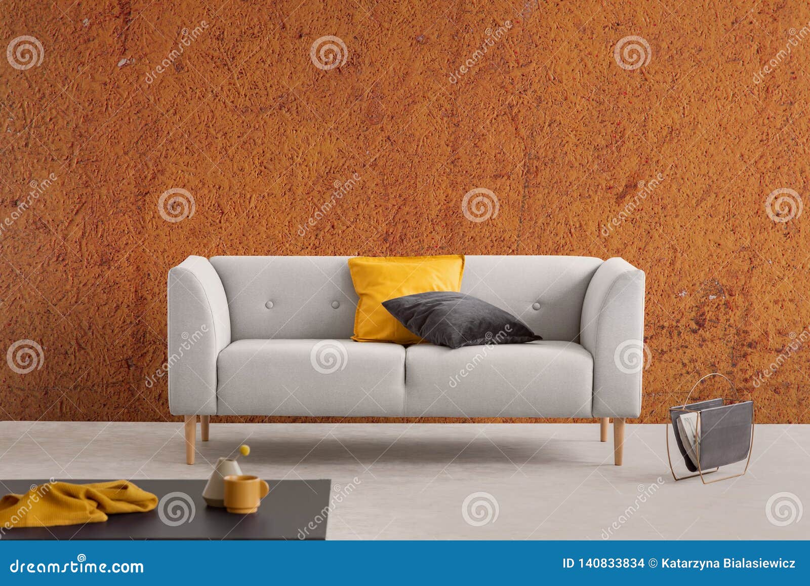 burnt orange wabi sabi living room interior with grey couch with yellow and black pillows and newspaper rack