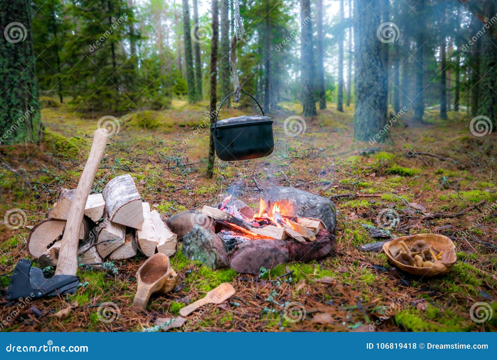 A Bushcraft Camp Fire with Hanging Pot, Axe and Kuksa. Stock Photo