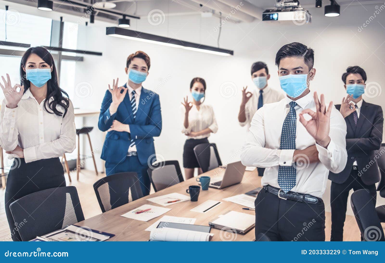 busines people wearing face mask and showing ok gesture . business meeting in modern office while pandemic of virus