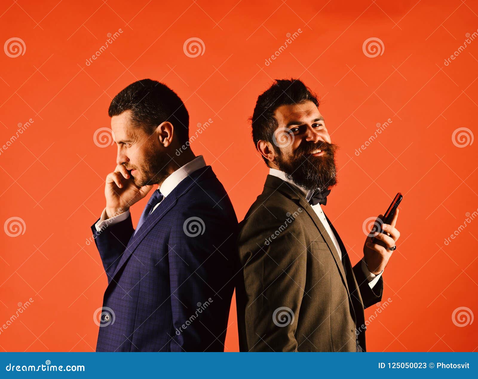business call. machos in classic suits talk on cell phone.