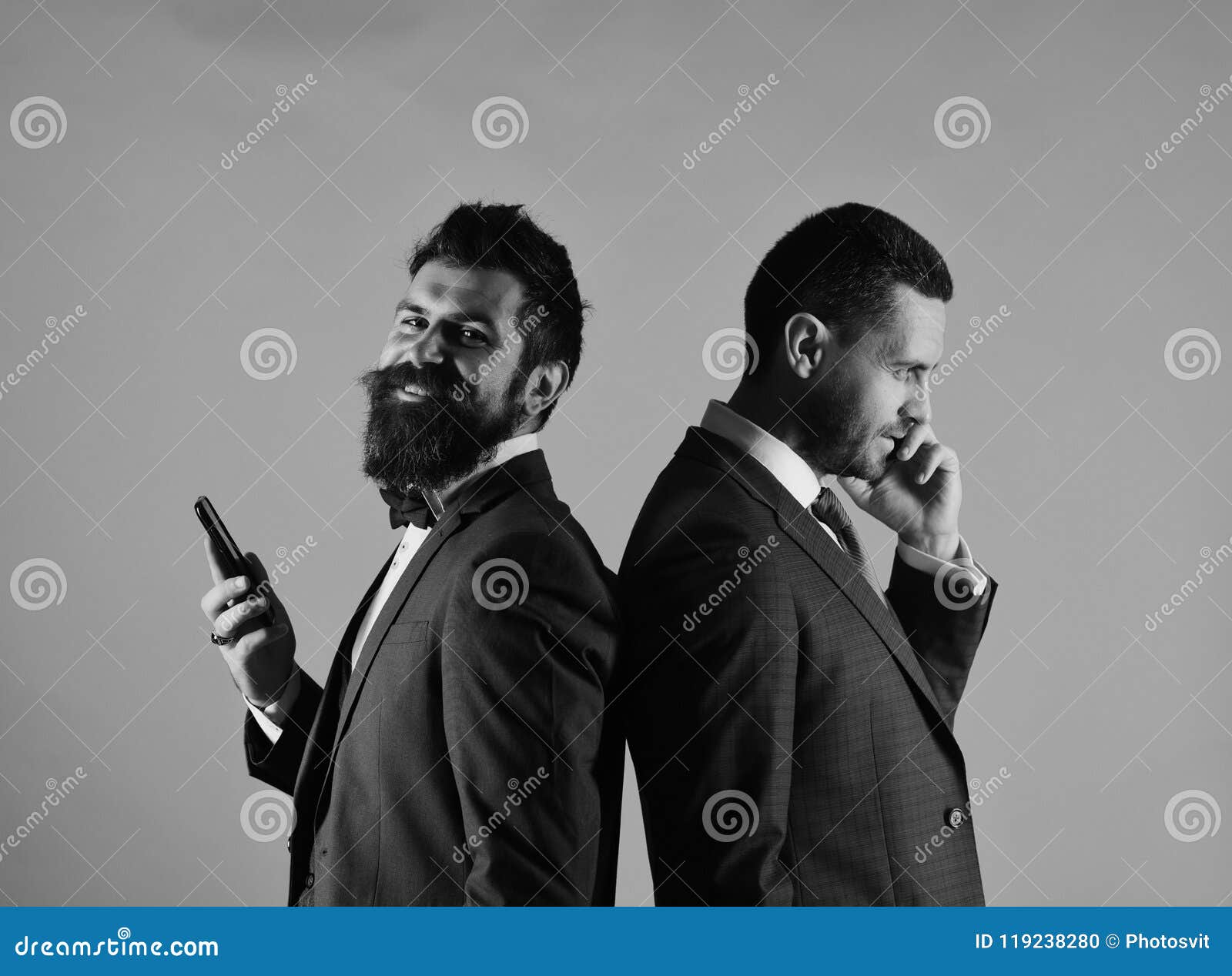 business call. machos in classic suits talk on cell phone.