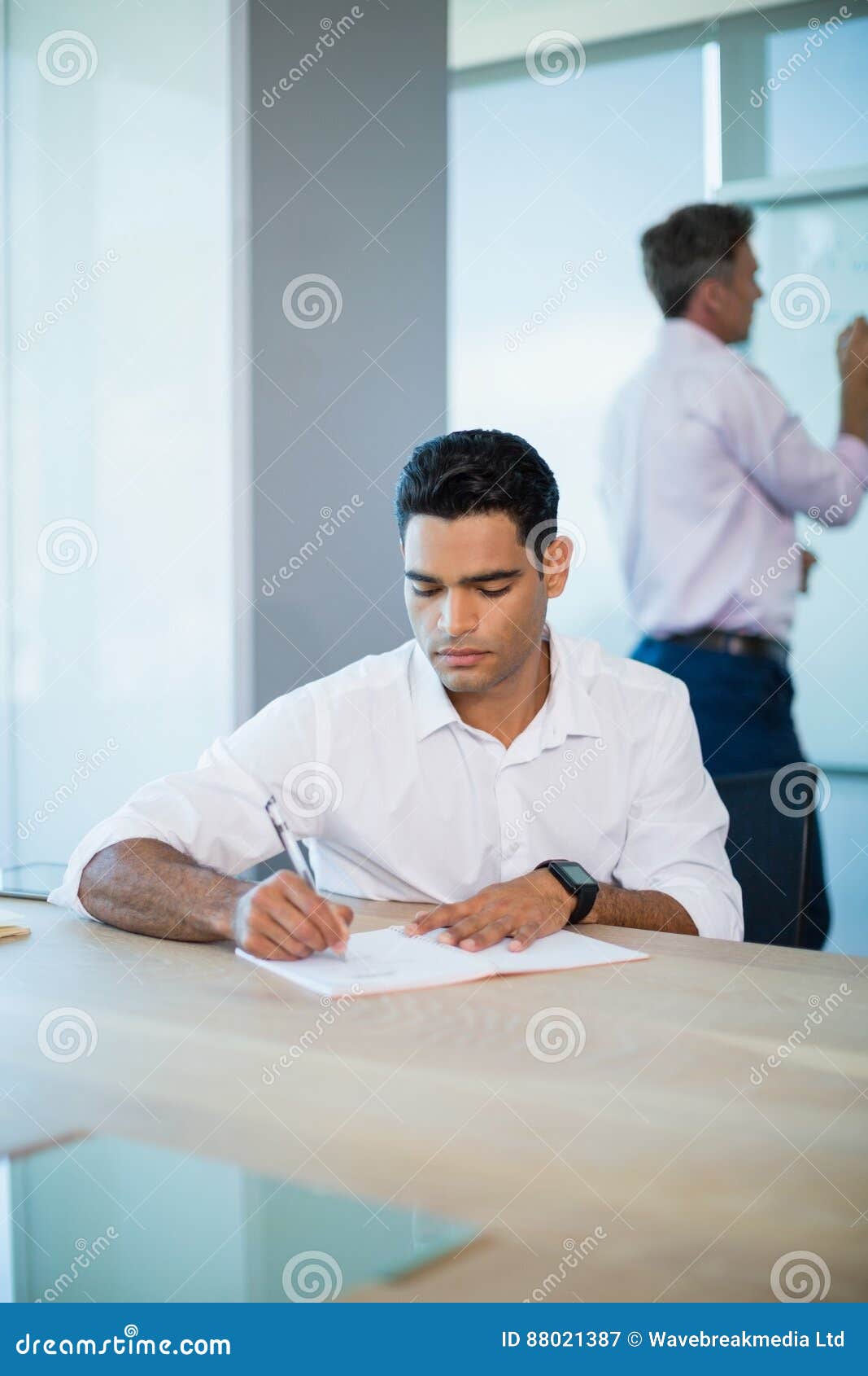 Business Executive Writing on Notebook in Conference Room Stock Image