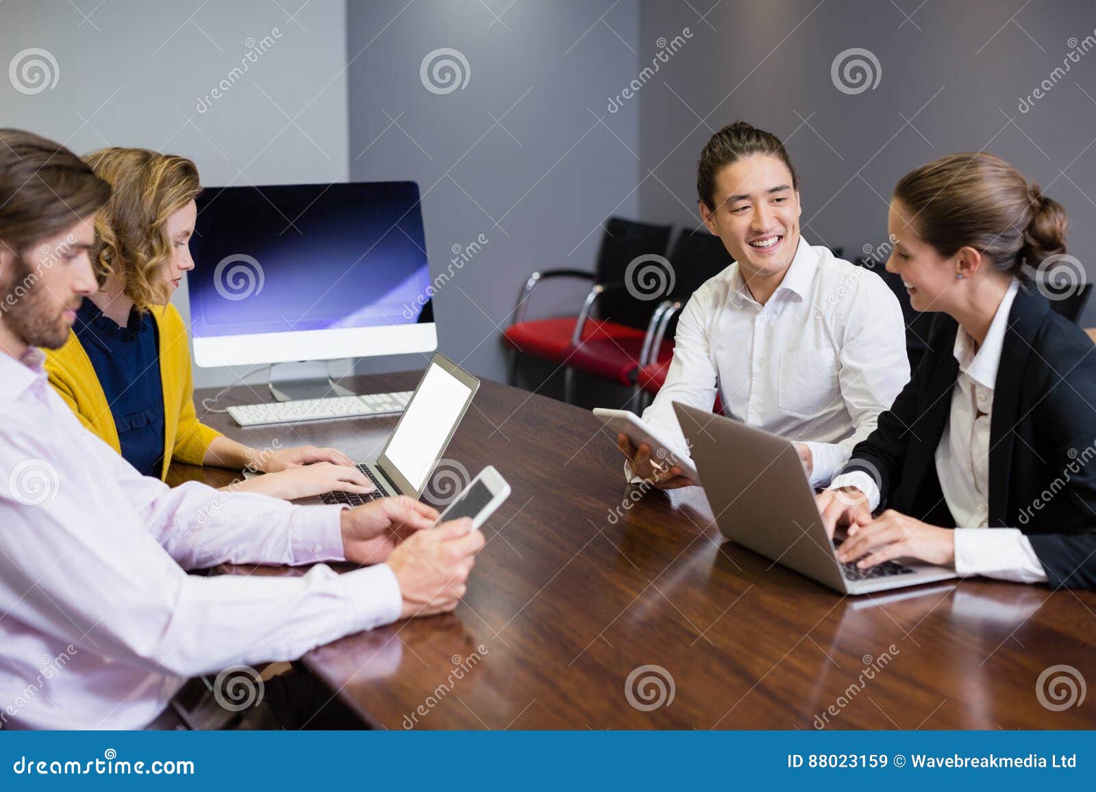 Business Executives Using Electronic Devices on Conference Table Stock
