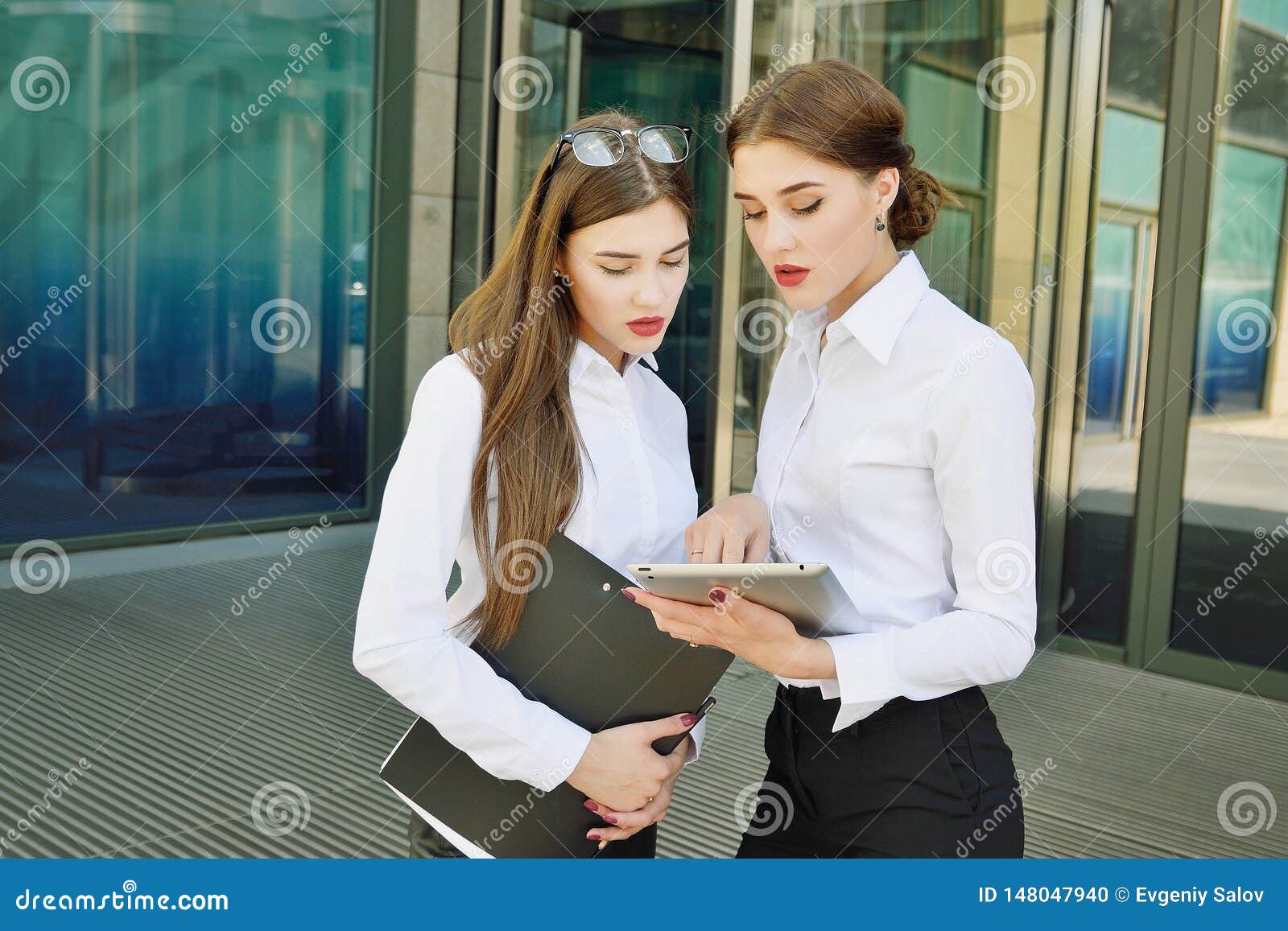 business lady. office staff. two young girls with electronic tablets communicate against