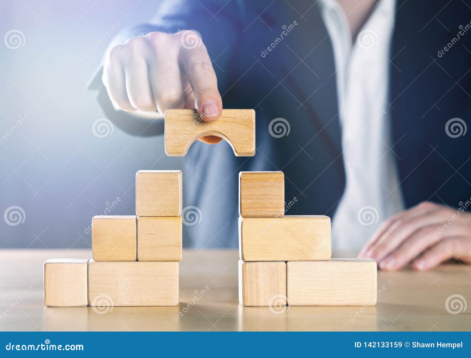 business man bridging the gap between two towers or parties made from wooden blocks; conflict management or mediator concept