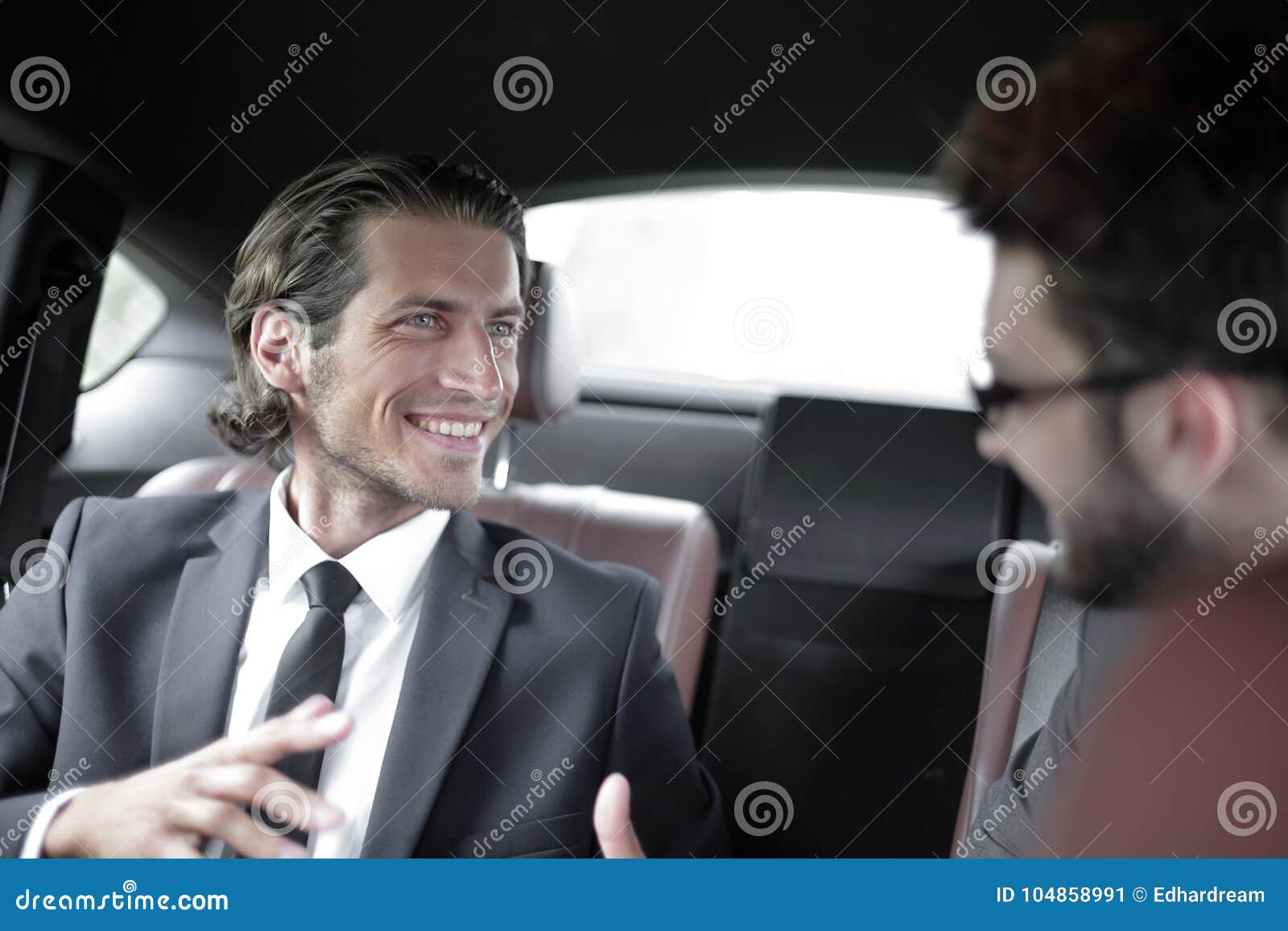 Business partners sitting on the backseat of the car. Business partners communicate ,sitting in the back seat of a car