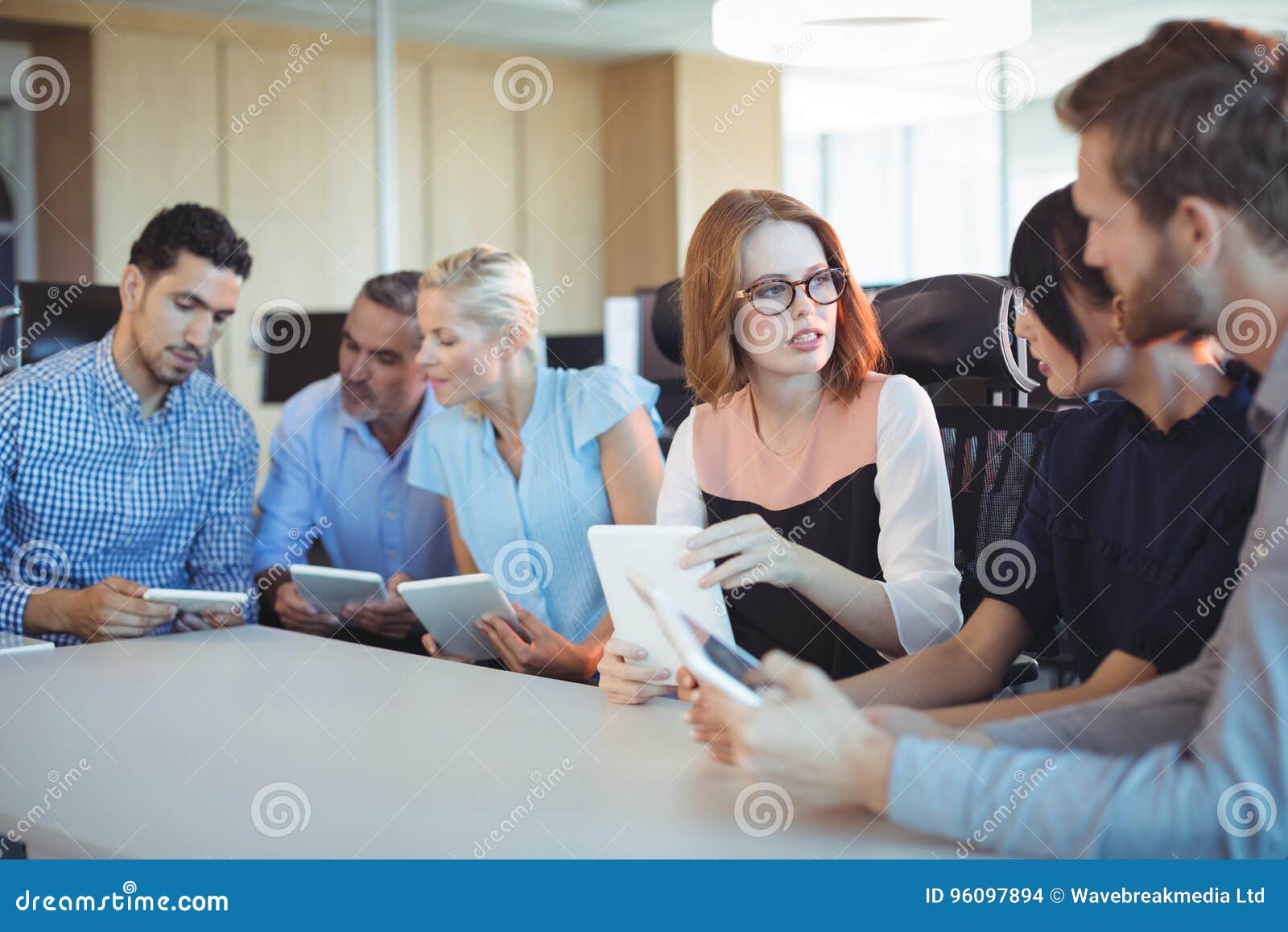 Business People Discussing While Holding Digital Tablets Stock Photo