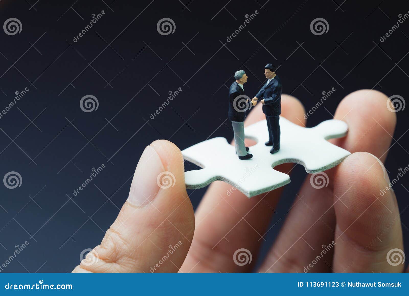 business success strategy with collaboration, teamwork or negotiation jigsaw key, miniature people businessmen handshaking on