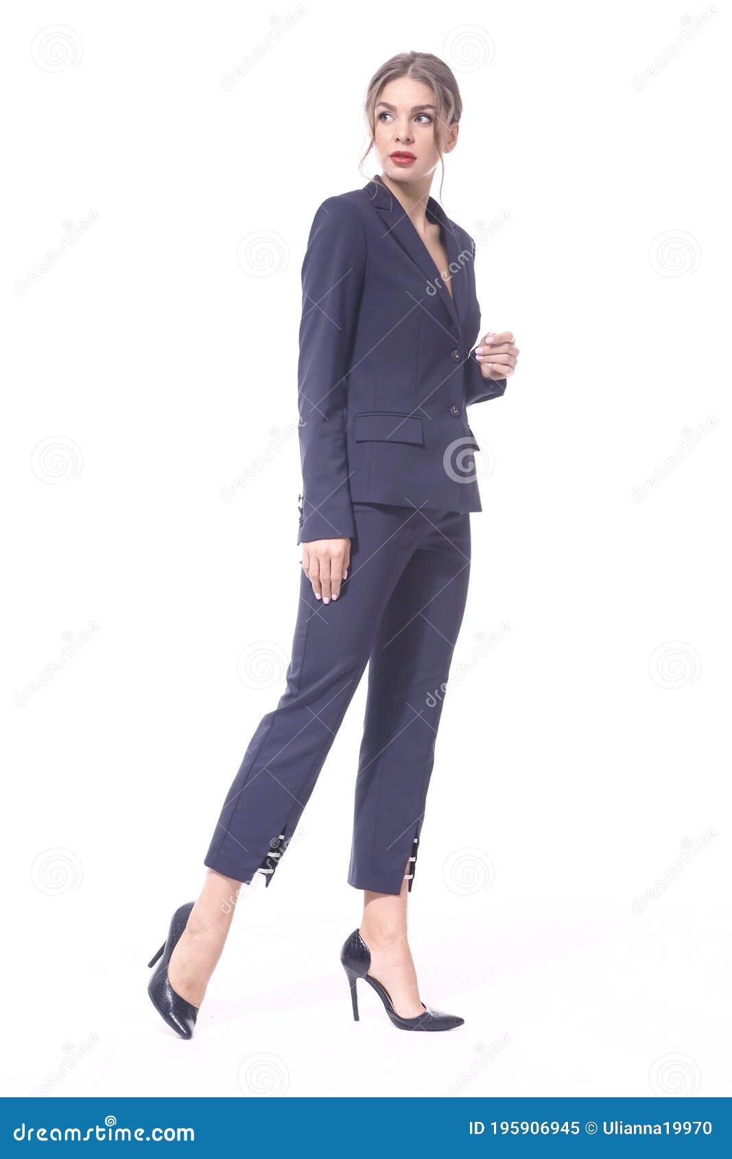 A beautiful slim woman in glasses and a trendy turquoise suit walks through  downtown. Pretty sexy business lady with slender legs in high heels is  walking down the city street. Slow motion.