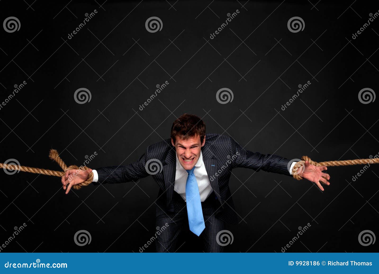 businessman being pulled by rope on both sides.