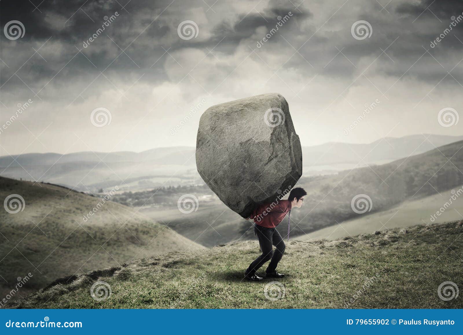 businessman carrying rock at hill