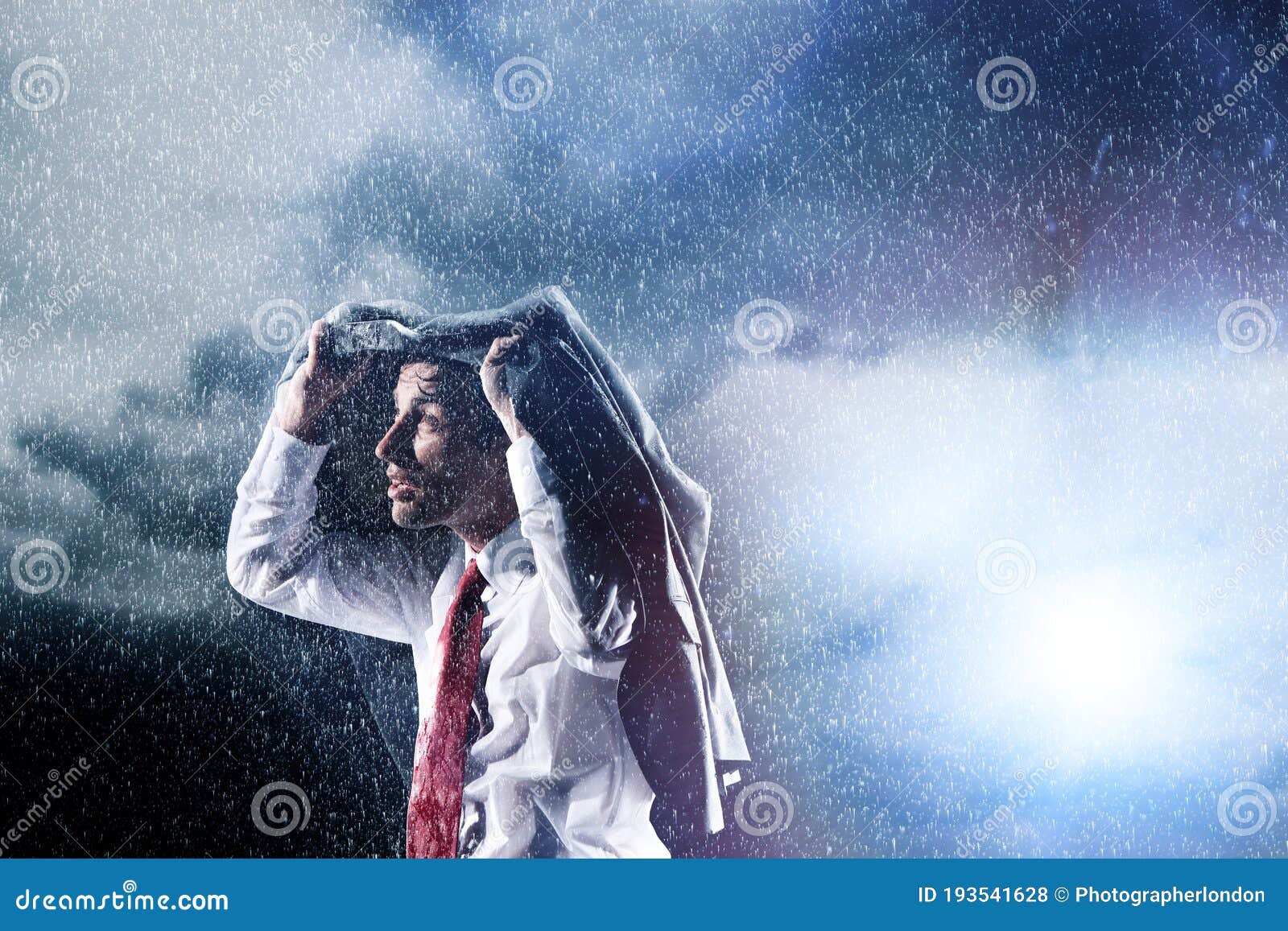 businessman caught in heavy rain hiding under his jacket