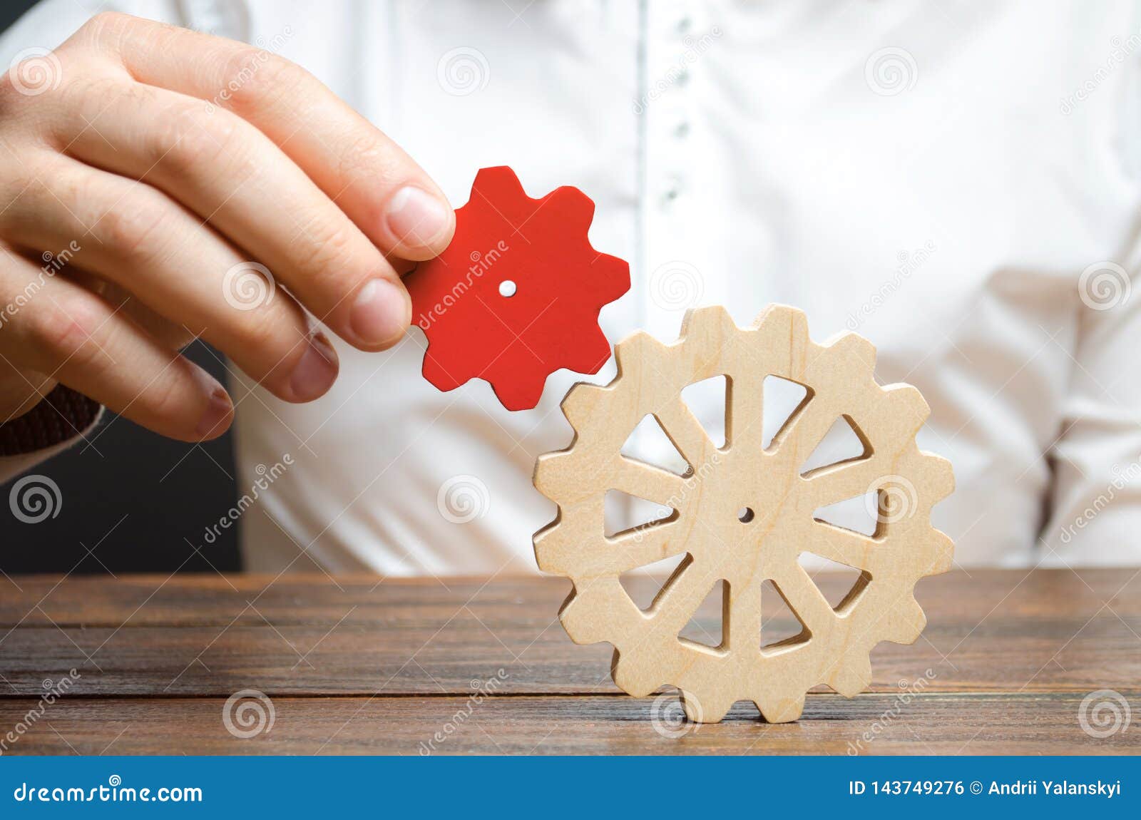 businessman connects a small red gear to a large gear wheel. ism of establishing business processes and communication.