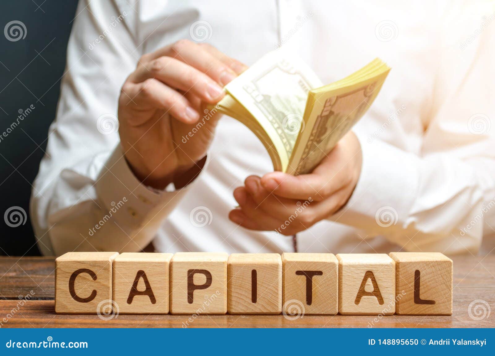 businessman counts money on the background of the caption capital. capitalism, capital increase and influence. financial