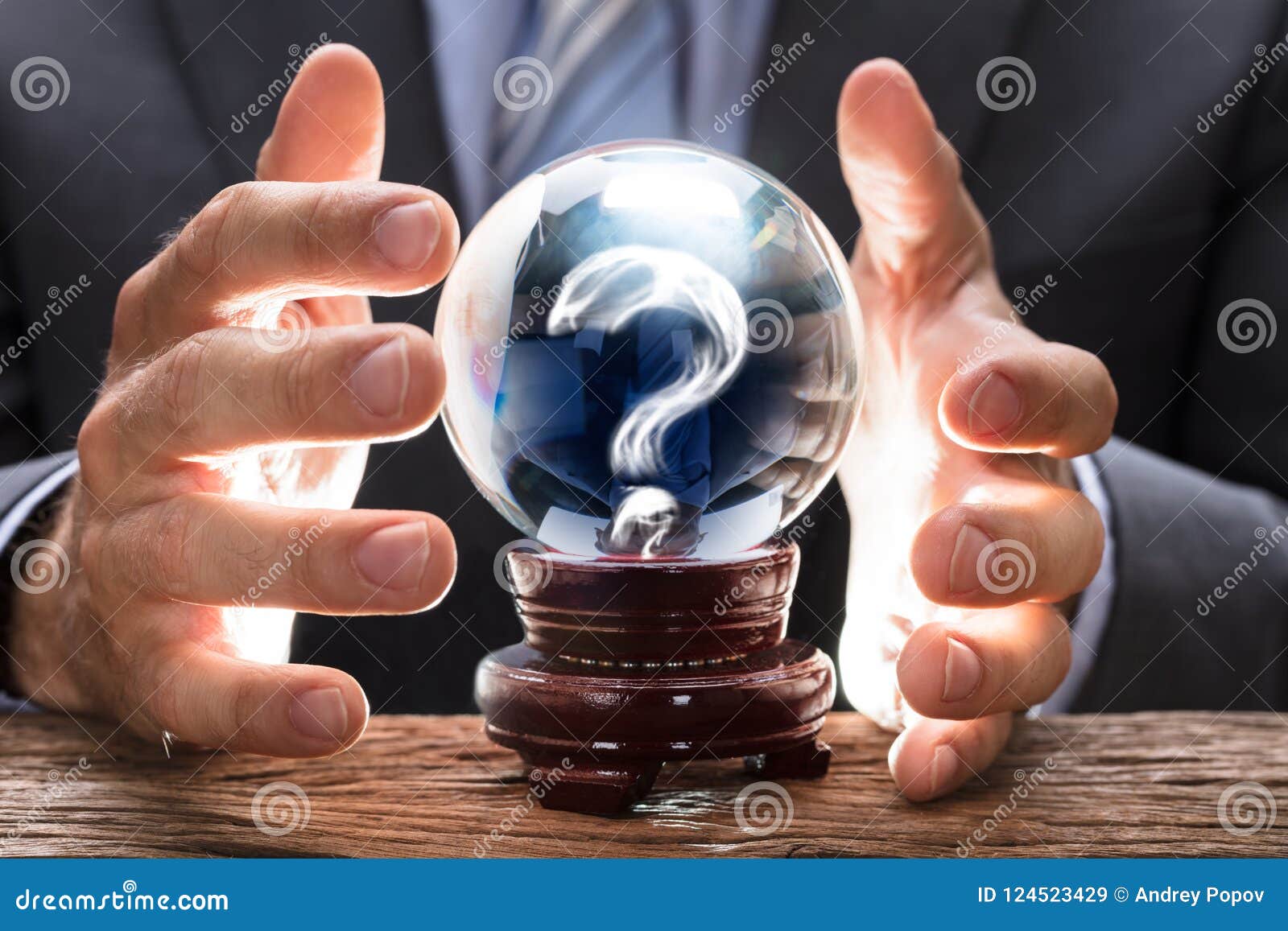 businessman covering crystal ball with question mark